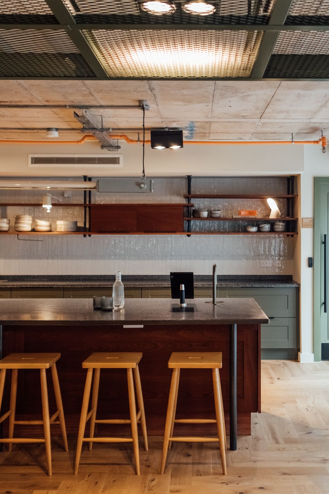 Co-working space within Hairpin House by 93. Kitchen counter with hot drinks-tap. Sage green door cabinets. 
